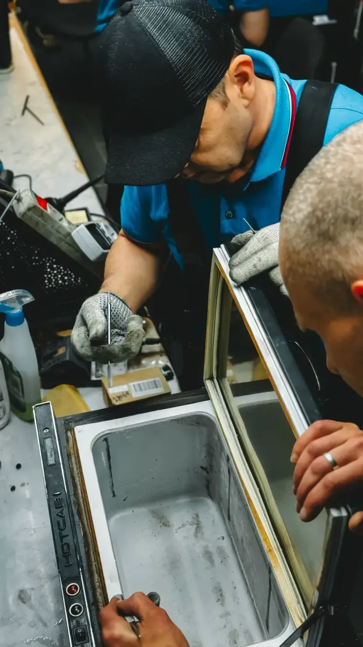 Técnicos abrindo um freezer para manutenção